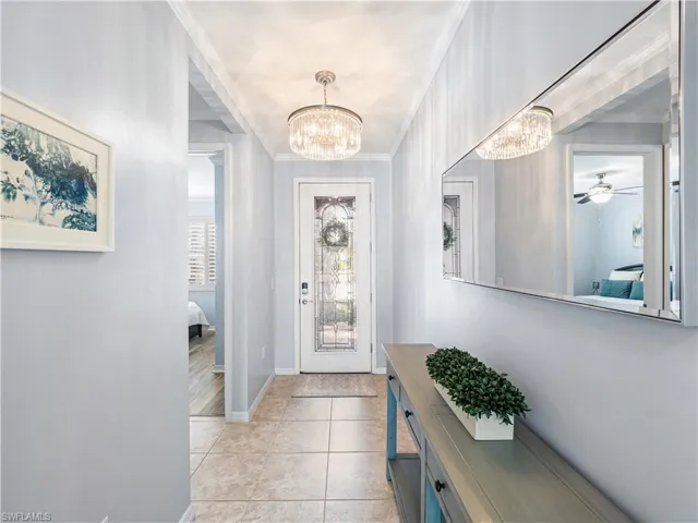 Entryway featuring a chandelier, ceiling fan, crown molding, and light tile patterned flooring