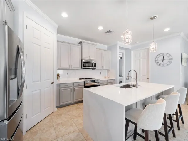 Kitchen featuring stainless steel appliances, decorative light fixtures, light stone countertops, gray cabinetry, and light tile patterned flooring