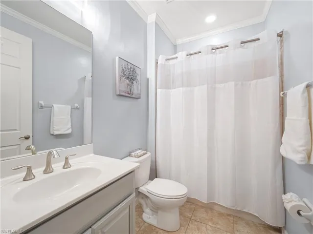 Full bathroom with crown molding, vanity, curtained shower, and light tile patterned floors