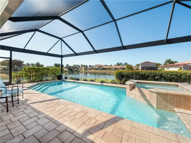Integrated pool / hot tub with a lanai, a sunroom, a water view, a residential view, and a patio area