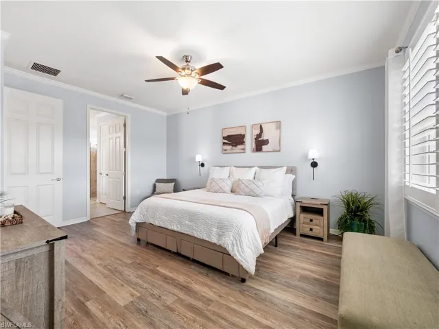Bedroom with ornamental molding, wood finished floors, and a ceiling fan