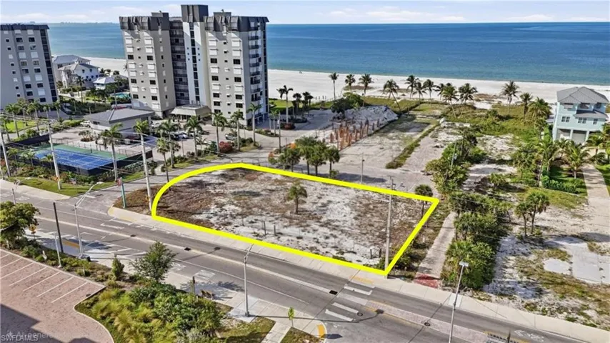 Cleared lot with street frontage, featuring a single palm tree, and a sidewalk along its perimeter - Virtually Edited Image