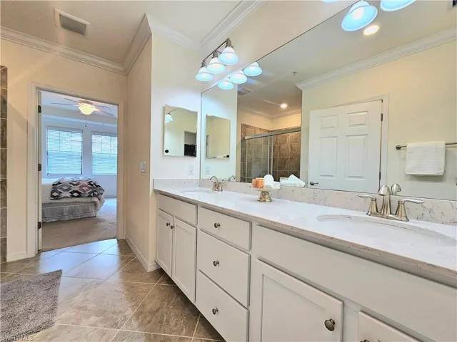 Bathroom with a shower stall, a sink, visible vents, and double vanity