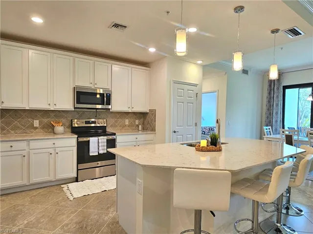 Kitchen featuring white cabinetry, appliances with stainless steel finishes, a sink, and visible vents