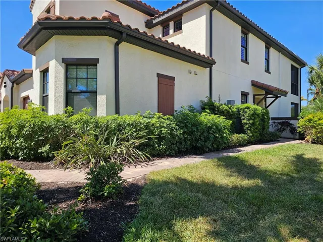 View of side of home with stucco siding, a yard, and a tiled roof