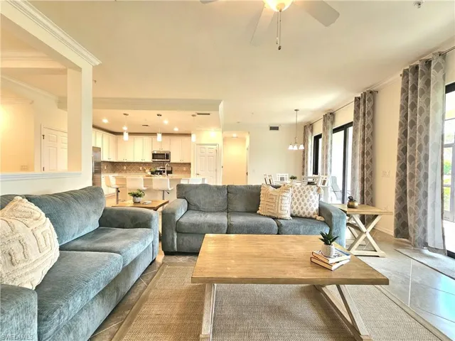 Living area featuring light tile patterned flooring, crown molding, and ceiling fan