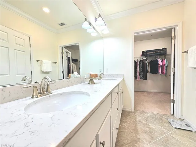 Full bath featuring a spacious closet, crown molding, a sink, and double vanity