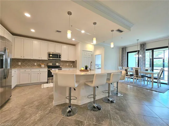 Kitchen with decorative backsplash, appliances with stainless steel finishes, crown molding, and visible vents
