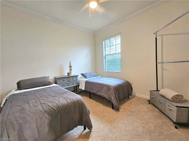 Carpeted bedroom with a ceiling fan, baseboards, and ornamental molding