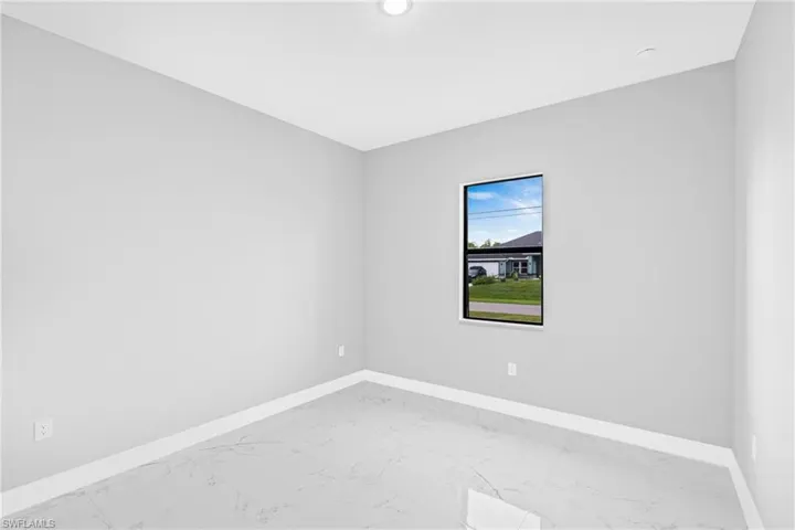 Unfurnished room featuring light marble finish flooring and baseboards