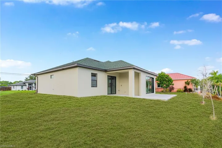 Back of property with stucco siding, a patio area, and a lawn