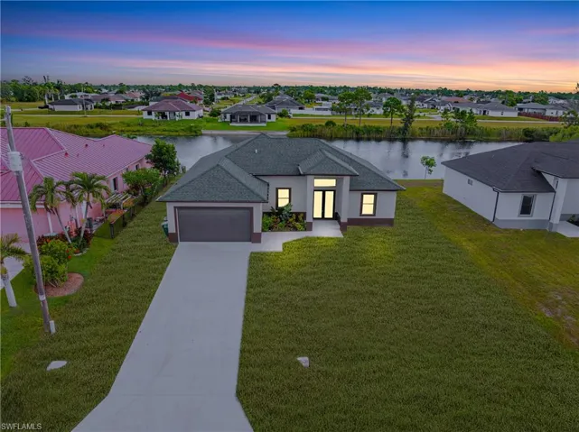 Ranch-style home with concrete driveway, a residential view, a garage, a water view, and a front yard