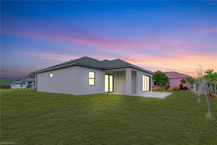 Rear view of house with stucco siding, a patio, and a lawn