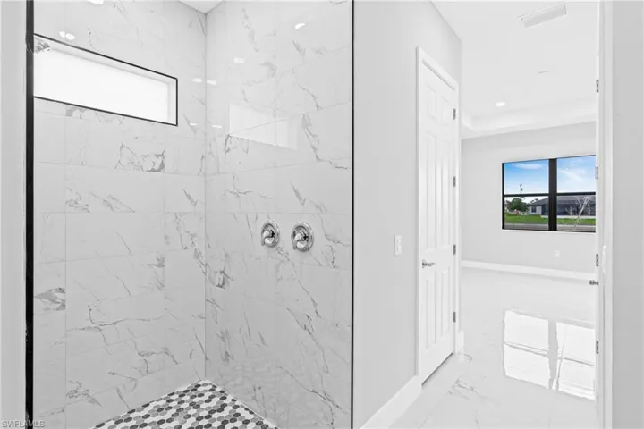 Bathroom featuring healthy amount of natural light, a marble finish shower, light marble finish floors, and recessed lighting