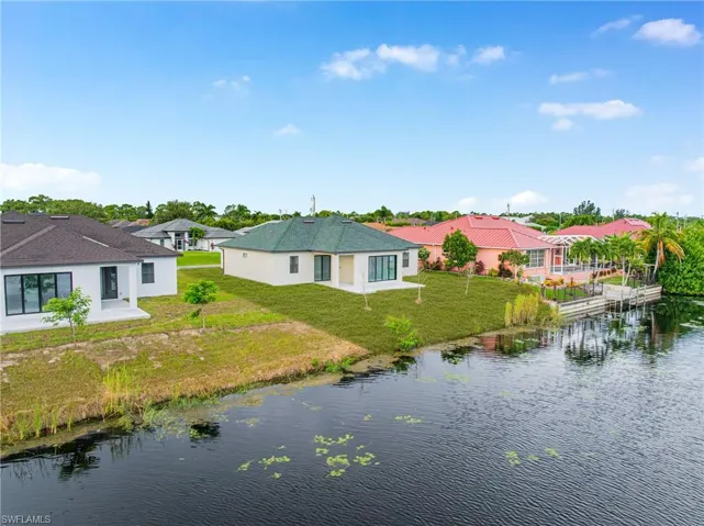 Back of property featuring a patio area, a yard, and a water view