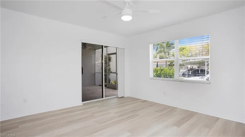 Primary bedroom featuring light wood finished floors, a ceiling fan, and baseboards. Slider opens to the lanai.