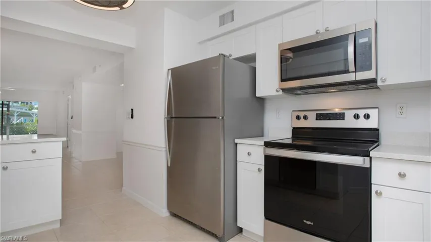 Kitchen with stainless steel appliances, light countertops, white cabinetry, and light tile patterned floors