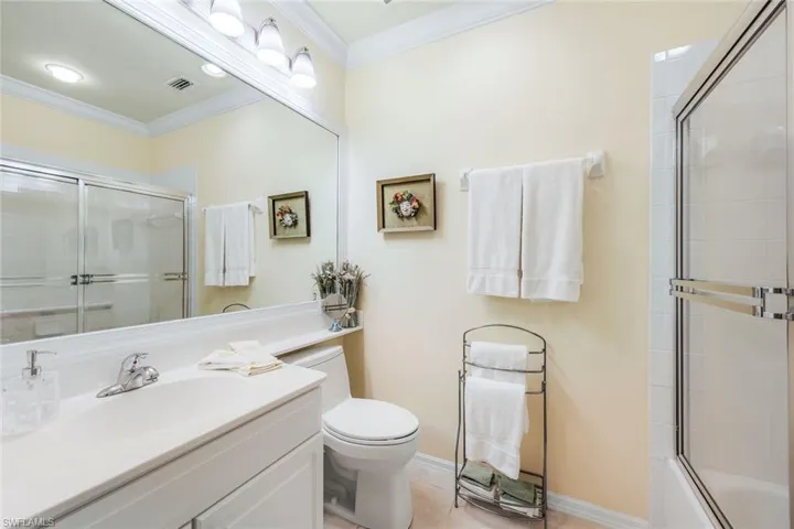 Full bathroom with combined bath / shower with glass door, toilet, vanity, tile patterned flooring, and ornamental molding