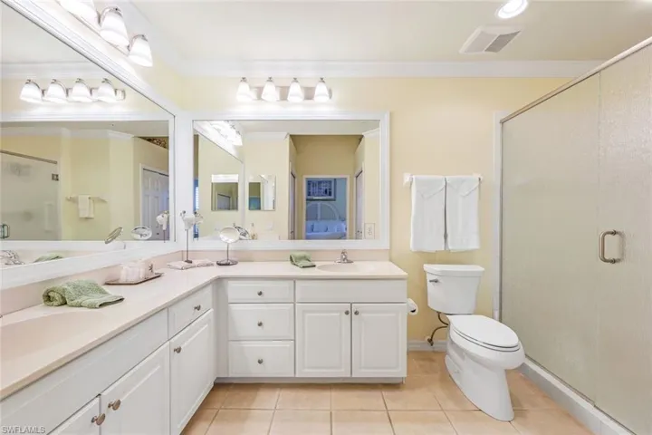 Bathroom with a shower with door, tile patterned floors, dual vanity, and toilet