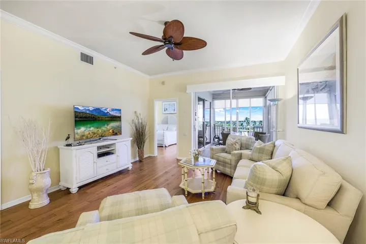Living room featuring ceiling fan, crown molding, and wood-type flooring