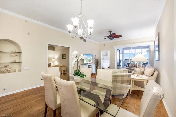 Dining area with built in features, ceiling fan with notable chandelier, ornamental molding, and hardwood / wood-style floors
