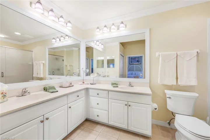 Bathroom featuring double sink vanity, ornamental molding, tile patterned floors, and toilet