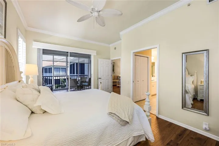 Bedroom featuring access to exterior, hardwood / wood-style floors, ceiling fan, ornamental molding, and ensuite bathroom
