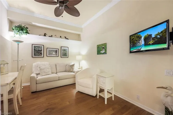 Living room featuring ceiling fan, crown molding, and dark hardwood / wood-style flooring