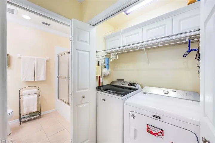 Laundry area featuring crown molding, light tile patterned flooring, and washing machine and clothes dryer