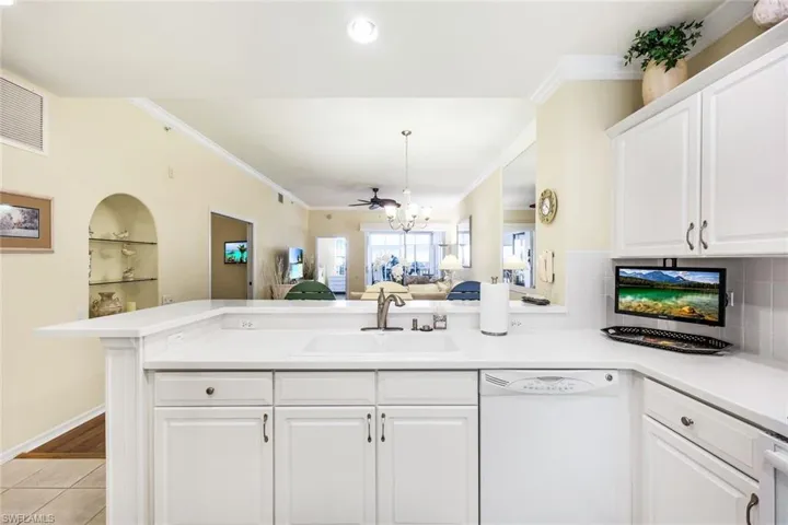 Kitchen with tasteful backsplash, white cabinetry, white dishwasher, light hardwood / wood-style flooring, and sink