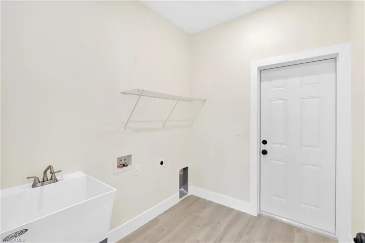 Washroom with light wood-type flooring, hookup for an electric dryer, and washer hookup