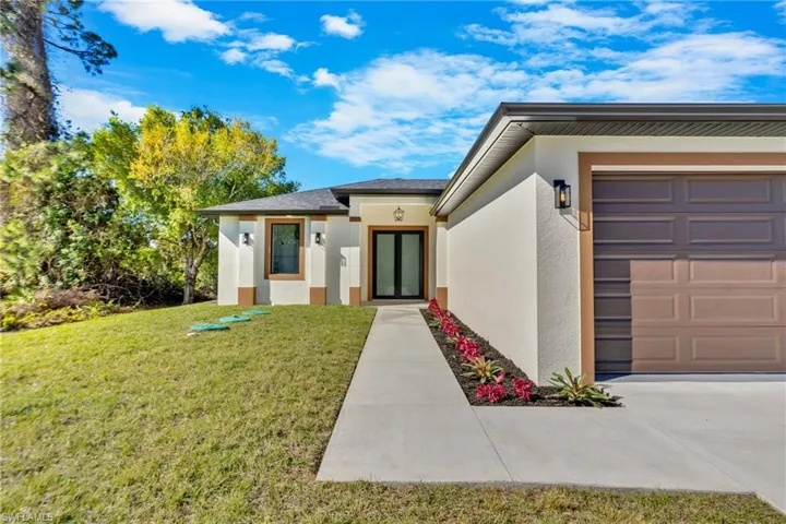 Property entrance featuring stucco siding, a lawn, and an attached garage