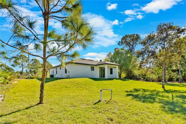 Back of property featuring a lawn and stucco siding
