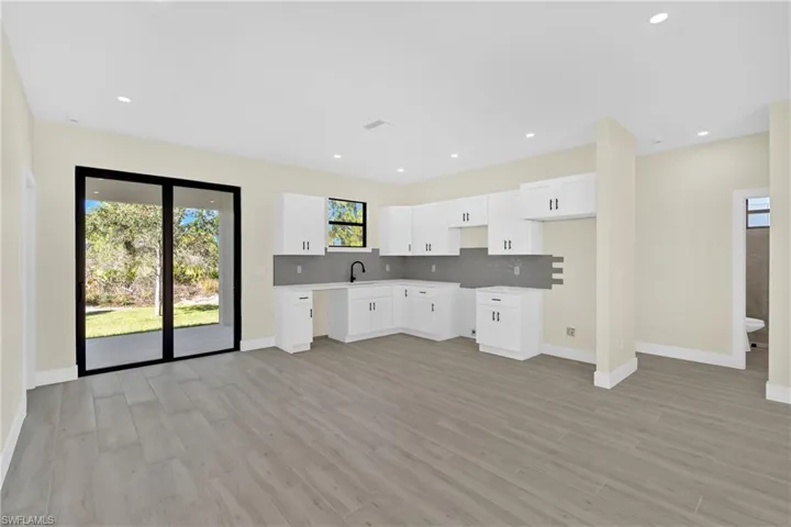 Kitchen featuring white cabinetry, decorative backsplash, light wood-type flooring, and recessed lighting
