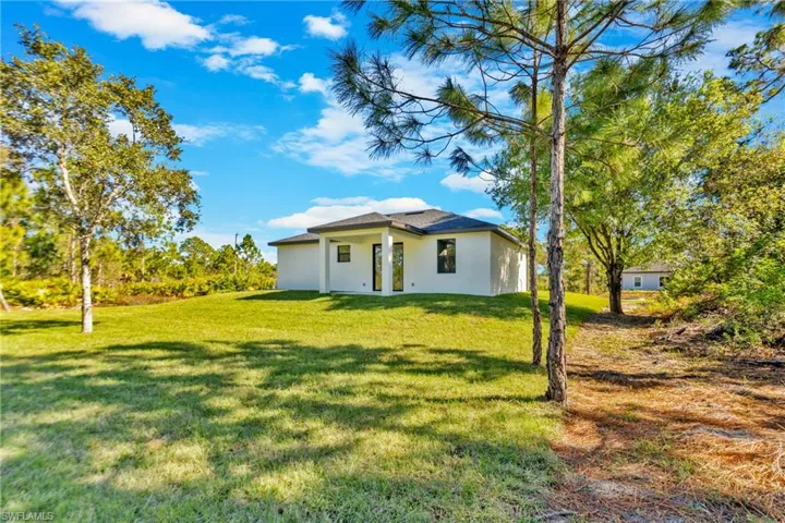 Back of house featuring stucco siding and a lawn