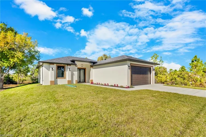 Prairie-style house featuring concrete driveway, a front lawn, stucco siding, and a garage