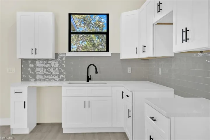 Kitchen with white cabinets, light stone countertops, tasteful backsplash, and light wood finished floors