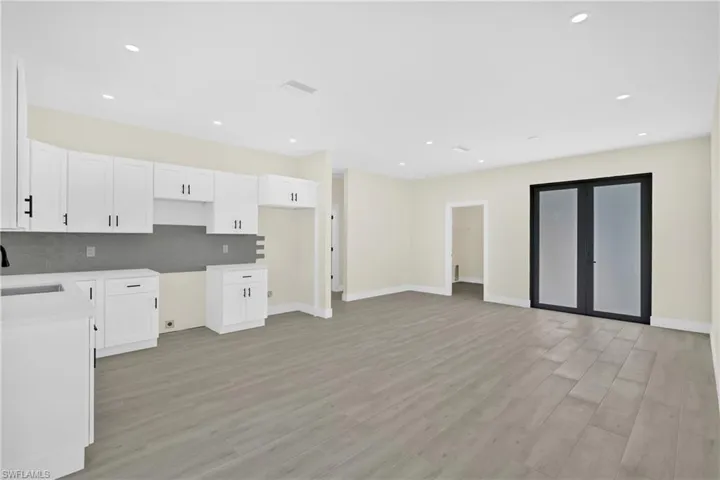 Kitchen featuring white cabinets, decorative backsplash, light wood-style floors, and recessed lighting