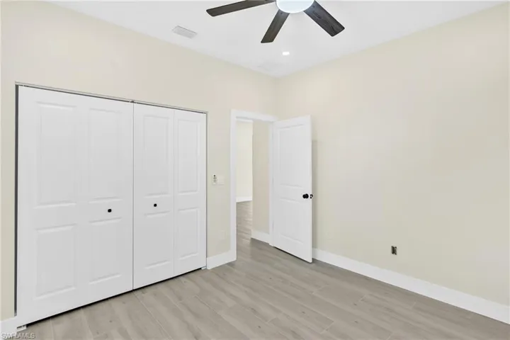 Unfurnished bedroom featuring wood finish floors, a ceiling fan, and a closet
