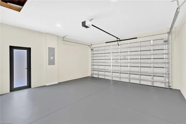 Garage featuring electric panel, a garage door opener, and recessed lighting