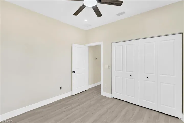 Unfurnished bedroom with light wood-style flooring, ceiling fan, and a closet