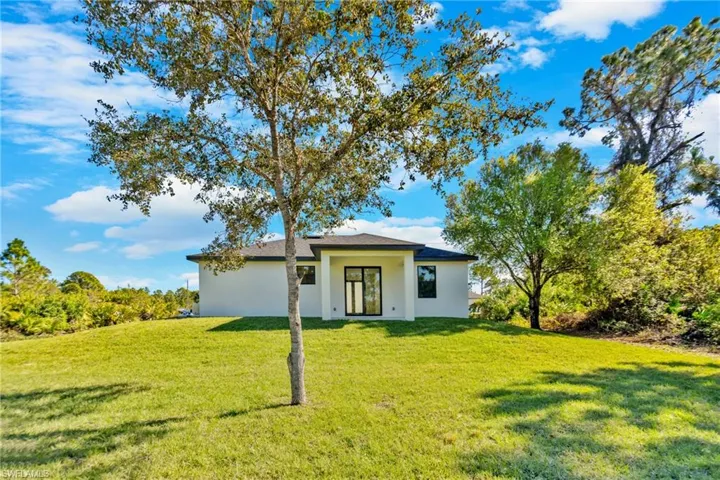 Rear view of property featuring a yard and stucco siding