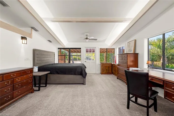 Bedroom featuring light colored carpet, access to exterior, a ceiling fan, an office area, and a raised ceiling