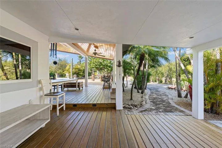 Wooden terrace with outdoor dining space and a ceiling fan