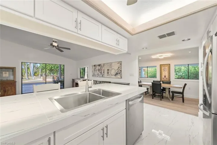 Kitchen featuring white cabinets, a ceiling fan, healthy amount of natural light, stainless steel appliances, and lofted ceiling