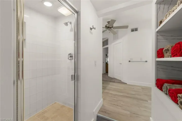 Full bathroom with a stall shower, light wood-type flooring, and ceiling fan