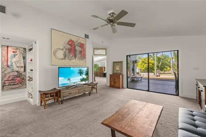 Living area featuring light carpet, ceiling fan, and lofted ceiling
