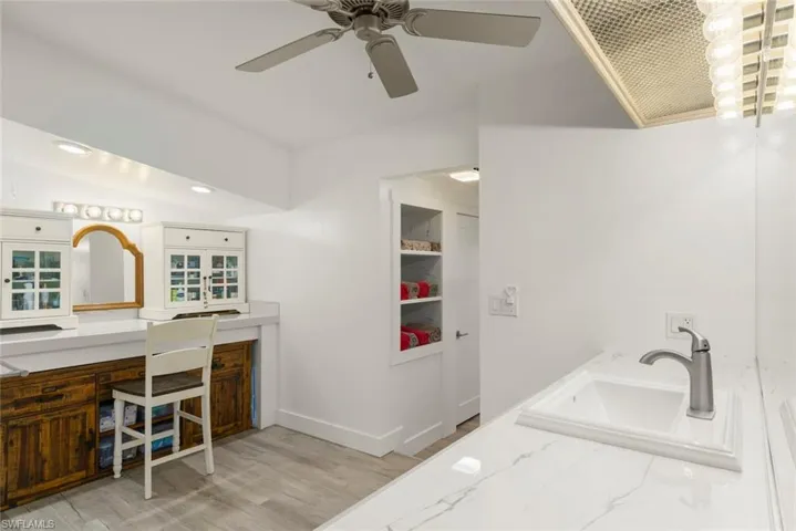 Full bathroom with double vanity, light wood-type flooring, and ceiling fan