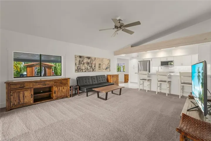 Living room featuring light carpet, ceiling fan, and vaulted ceiling