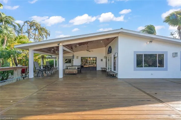 Wooden terrace with a ceiling fan and outdoor dining area